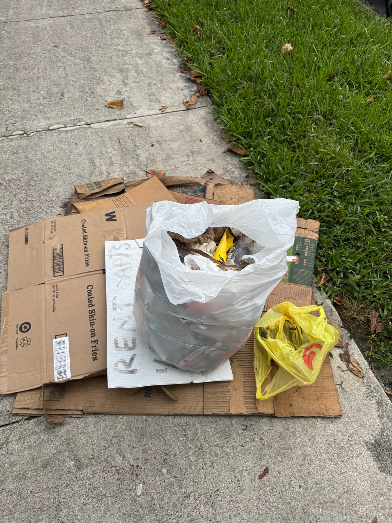 Bottles and cans gathered on flattened cardboard by the curb