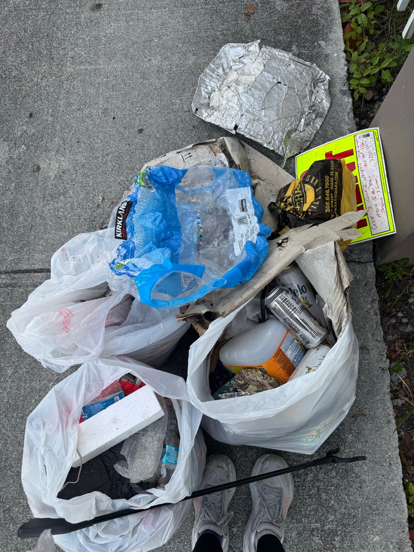 Bottles, cans, and a discarded sign cleared from the sidewalk